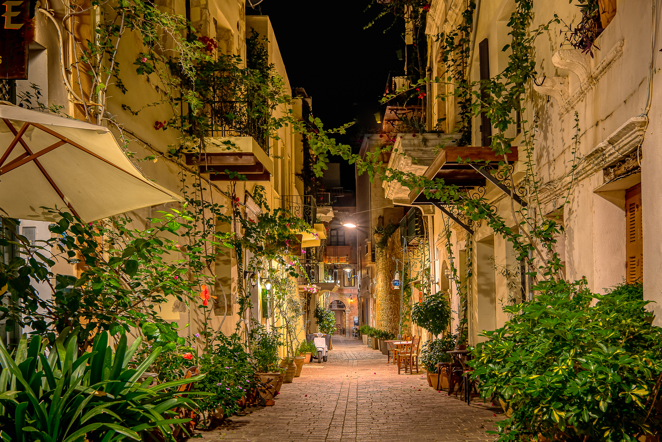 The illuminated alley Antoni Gampa with green plants and balconies in the old town of Chania, Crete, Greece, October 13, 2021